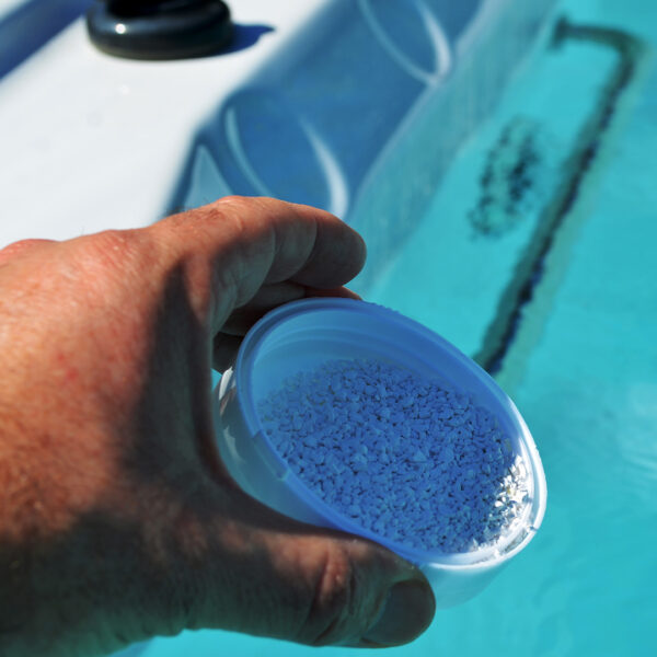 A person adding chemicals to a hot tub