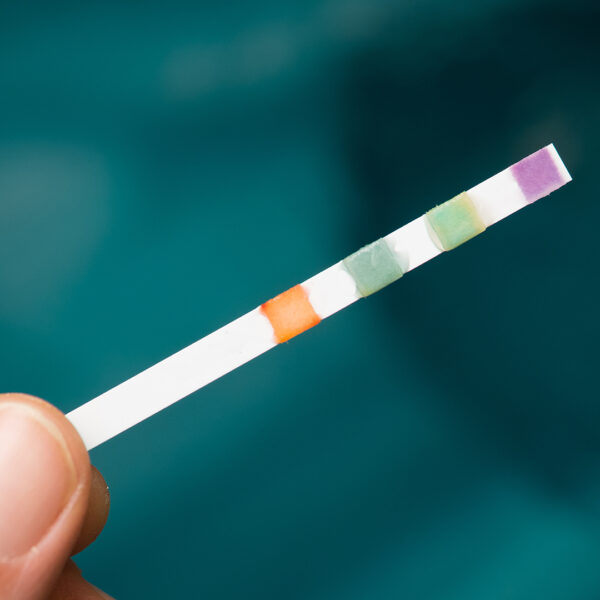 A person checking the pH balance of hot tub water